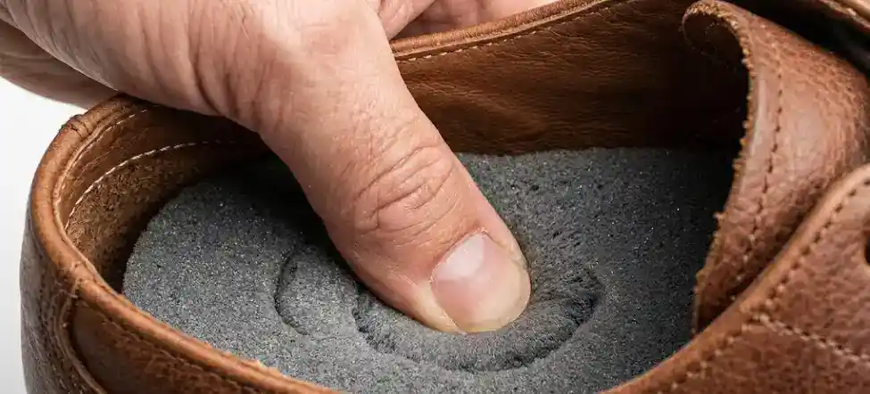 The Cushion Test thumb pressing into leather shoe insole cushion test yielding foam white daylight